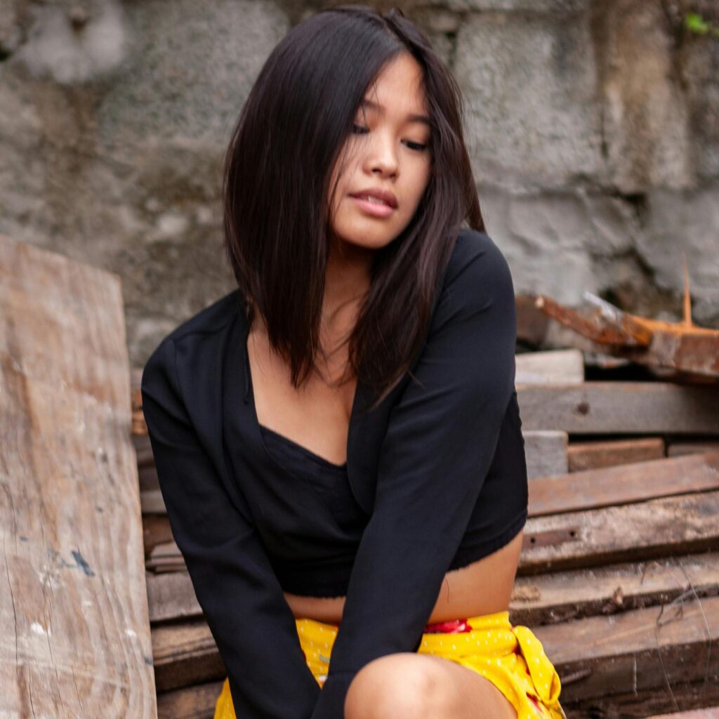 asian woman in yellow skirt sitting on logs