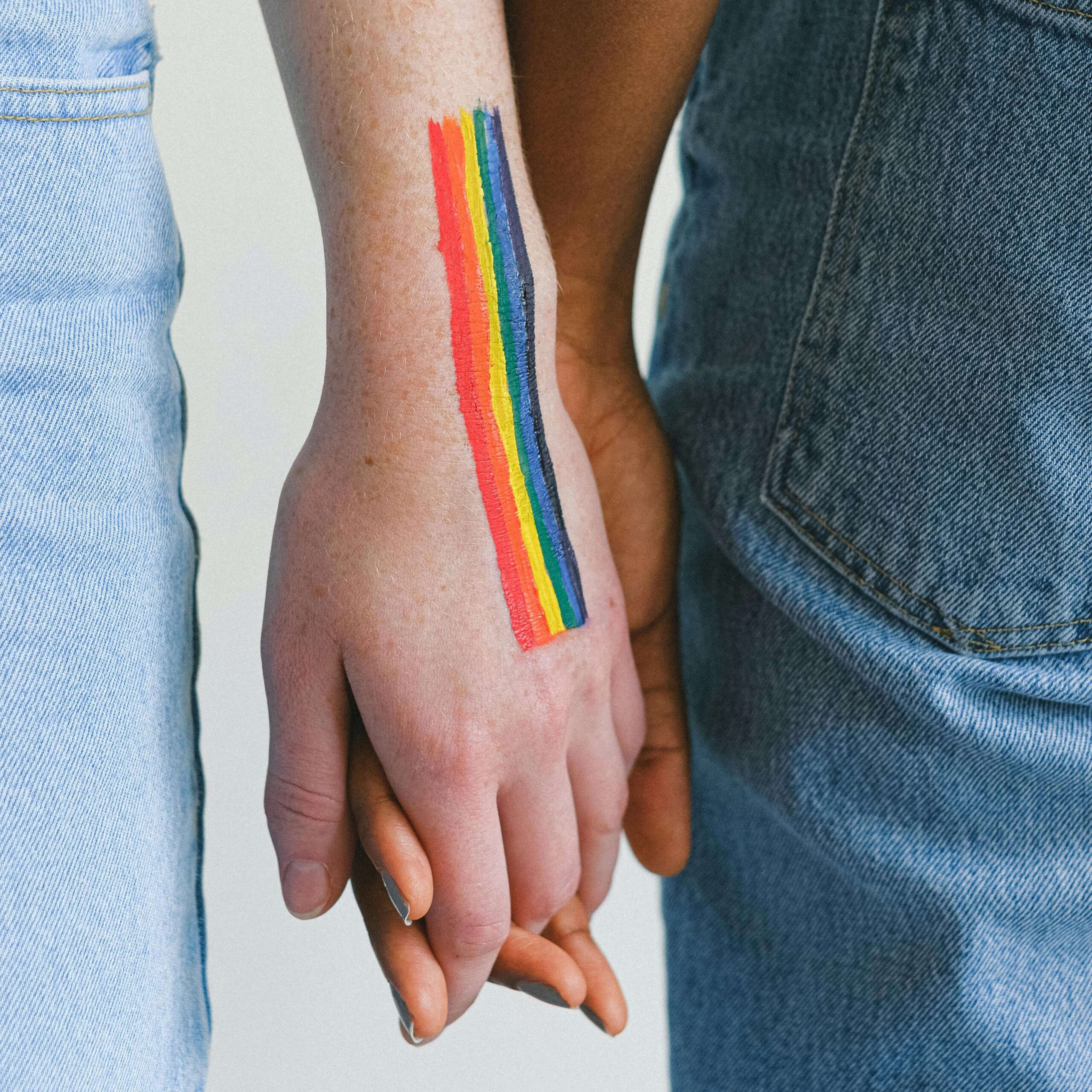 pexels two people holding hands with rainbow on one hand scaled